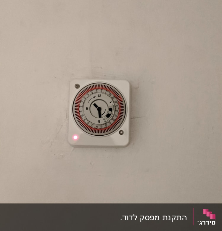 טיימר חשמלי על קיר עם נורית אדומה דולקת